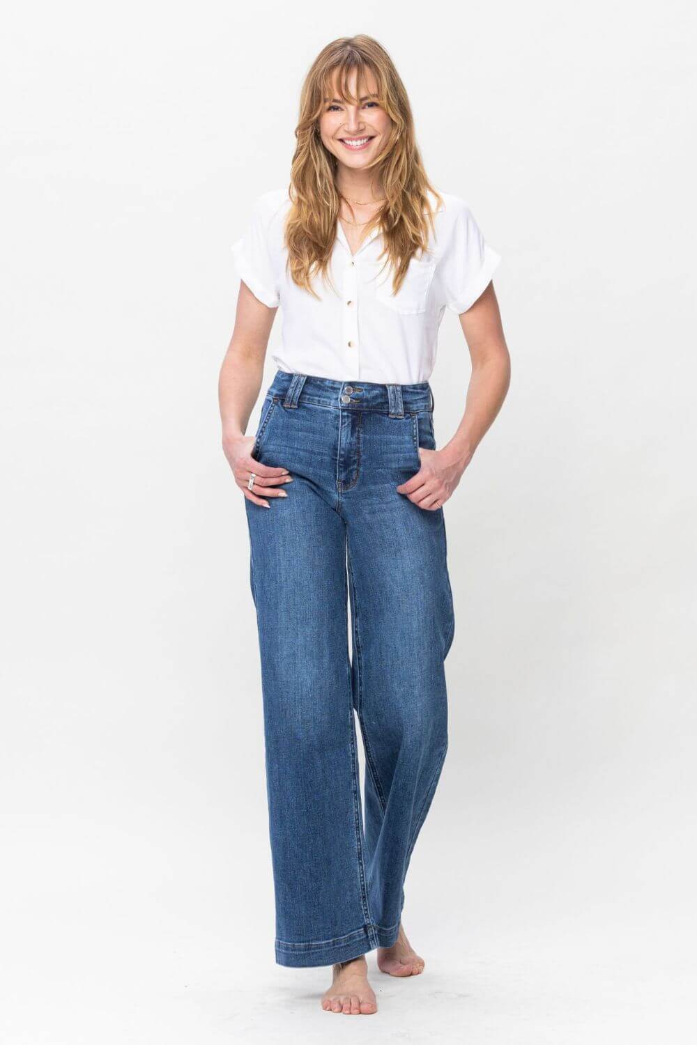 Woman wearing Judy Blue double button wide leg jeans, featuring a high rise and moderate stretch, paired with a white blouse.