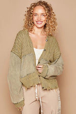 Trendy woman in a green distressed hem hooded cardigan, showcasing style and comfort with a cheerful smile.