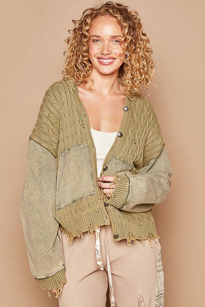 Trendy woman in a green distressed hem hooded cardigan, showcasing style and comfort with a cheerful smile.