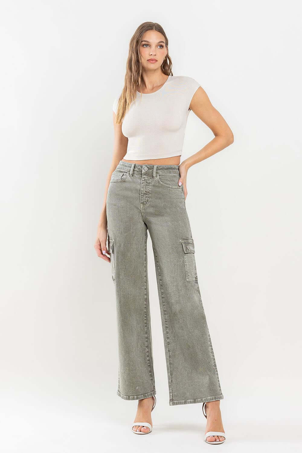 Woman wearing 90's Super High Rise Loose Cargo Jeans with ultra-high waist, cargo pockets, and a relaxed fit, paired with a white crop top.