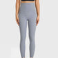 Woman in high waist grey leggings and black crop top, showcasing athleisure style for yoga or casual wear.