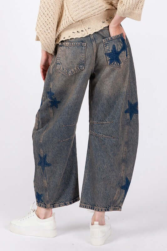 Rear view of SAGE + FIG Star Wide Leg Jeans featuring blue star patterns and functional pockets, styled with a cozy sweater.