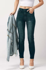 Woman wearing mid-rise waist skinny jeans with pockets and holding denim jacket