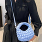 Woman holding Bella Road quilted puffy crossbody bag with removable strap, styled as a clutch, in a fashionable setting.