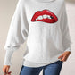 Woman wearing Bella Road Lip Turtleneck Long Sleeve Sweater in white, featuring a bold red lip graphic, paired with blue jeans.