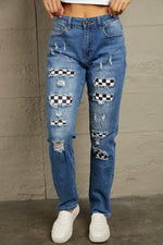 Mid waist distressed jeans with checkered patchwork, shown in a flat lay style, perfect statement piece for edgy fashion