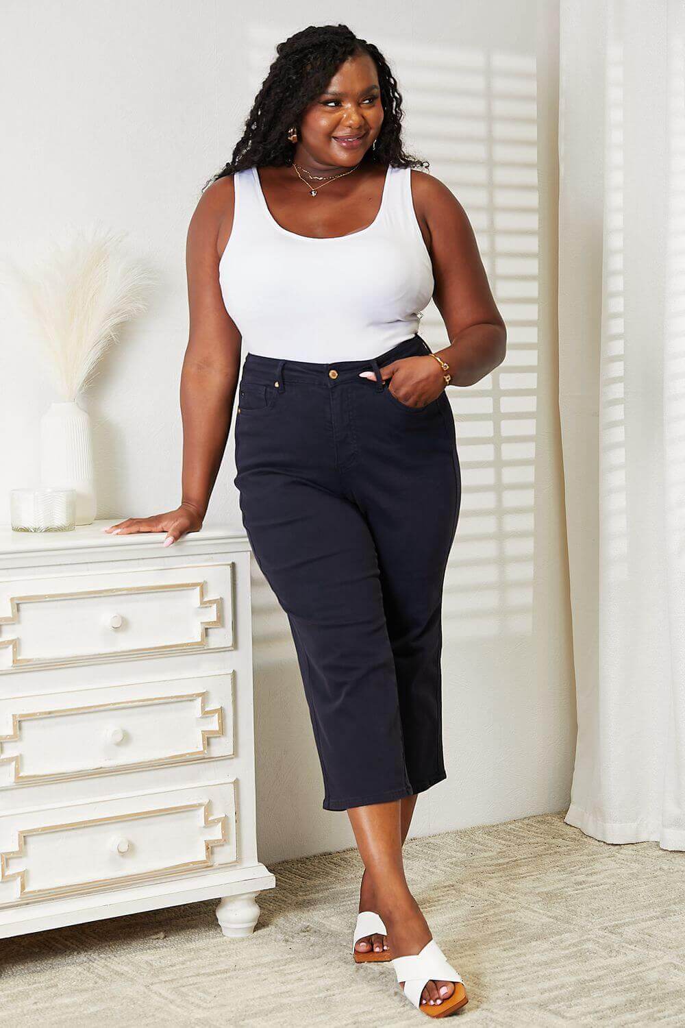 Woman wearing High Waist Tummy Control Garment Dyed Wide Cropped Judy Blue Jeans with a white tank top and sandals