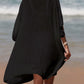 Woman in black cutout V-neck three-quarter sleeve cover up walking on beach. Openwork sheer fabric, no stretch. Cotton-polyester blend.