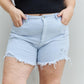 Woman wearing Katie High Waisted Distressed Shorts in Ice Blue by Risen Jeans, showcasing trendy style and comfortable fit