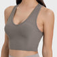 Stylish woman in a sleeveless, scoop neck, olive green active tank top, perfect for workouts and casual wear.