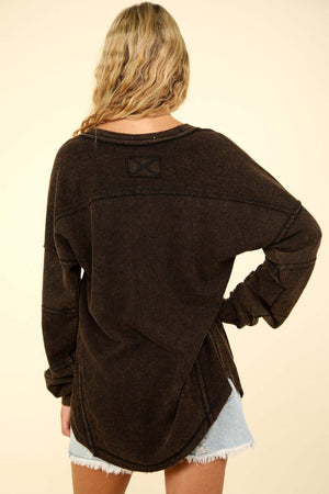 Back view of a woman wearing the VERY J Washed V-Neck Exposed Seam Knit Top in black with drop shoulder and long sleeves.