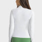 Back view of Millennia Half Zip Thumbhole Sleeve Sports Top in white, paired with green leggings, perfect for workouts.