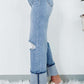 Woman wearing distressed straight jeans with pockets, slight stretch, and stylish cuffed hems. Paired with trendy sneakers against a chic background.