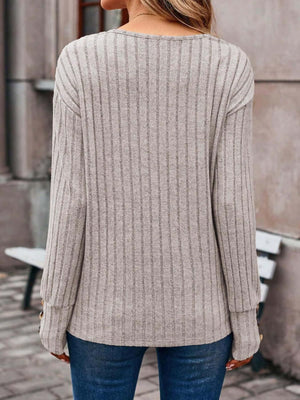 Back view of a gray ribbed V-neck long sleeve T-shirt with decorative buttons, worn with blue jeans.