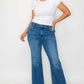 Woman modeling trendy mid rise ankle jeans with a white tee, showcasing a stylish casual outfit.