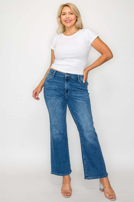 Woman modeling trendy mid rise ankle jeans with a white tee, showcasing a stylish casual outfit.