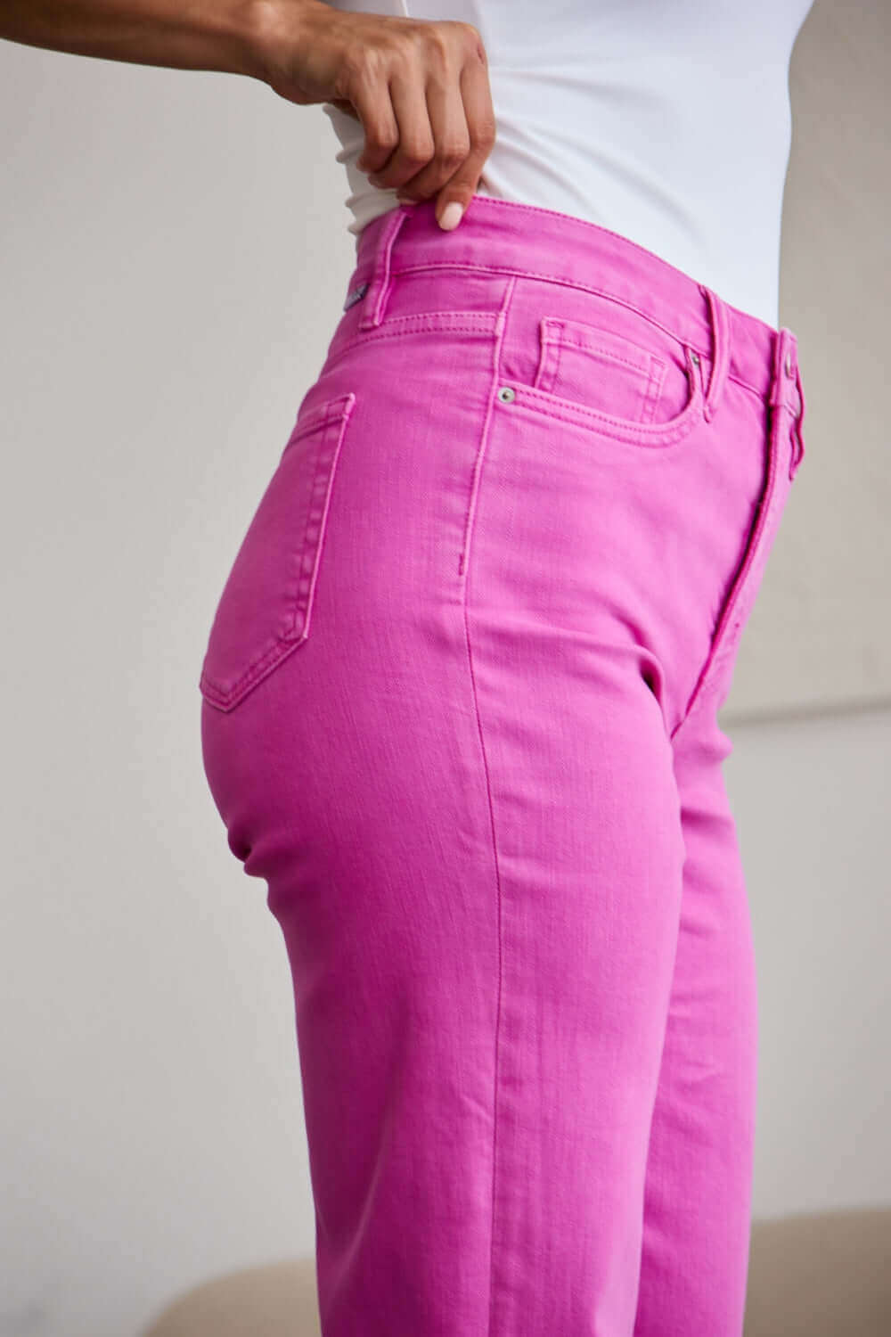 Woman wearing pink high waist RFM jeans with tummy control and raw hem, showcased with a close-up side view.