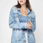 Fashion model wearing a Distressed Long Sleeve Denim Jacket by Risen Jeans, paired with white shorts and a blue top for a cool, casual look