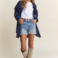 Stylish woman wearing J.NNA Rhombus Stitched Button Up Denim Shacket, paired with denim shorts and beige boots.