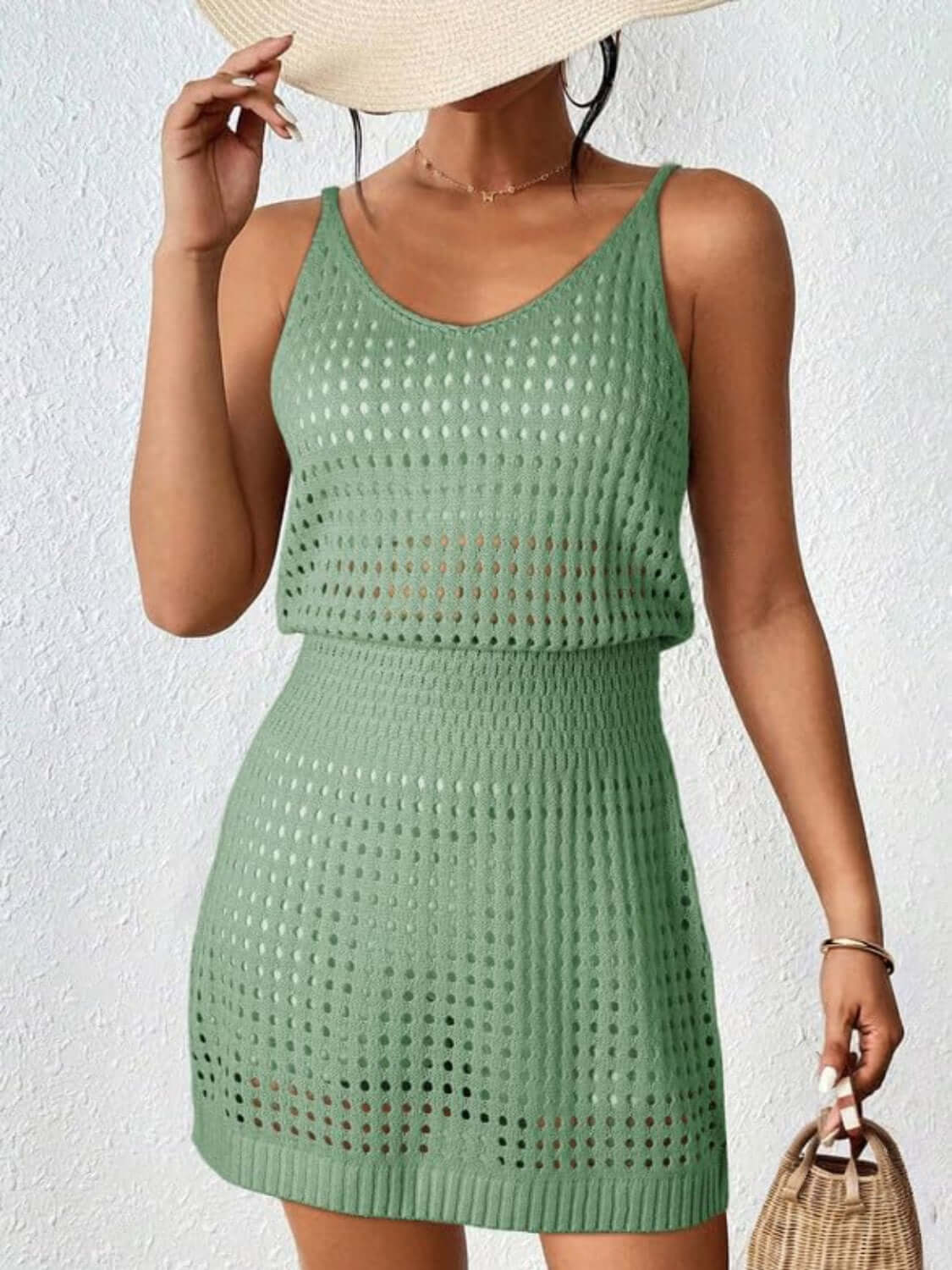 Woman wearing a green openwork V-neck sleeveless cover up dress made of stretchy, sheer acrylic material.