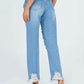 Rear view of woman wearing Raw Hem Distressed Straight Jeans in light wash denim with frayed edges and black heeled sandals