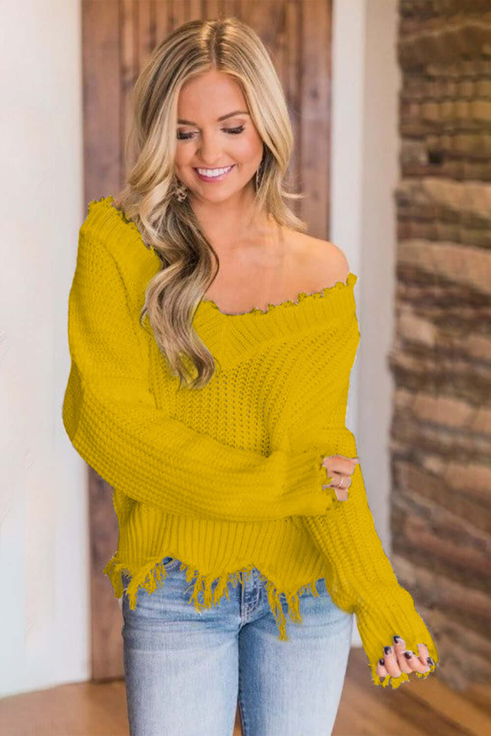 Woman wearing Bella Road frayed hem dropped shoulder yellow sweater with jeans, showcasing playful fashion style.