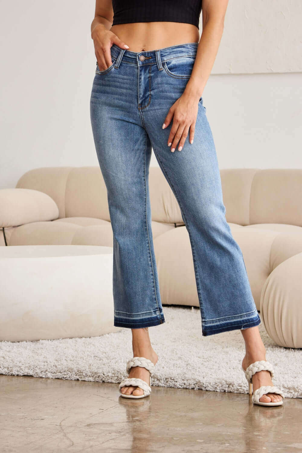 Woman wearing release hem cropped bootcut Judy Blue Jeans with a stylish look in a cozy indoor setting.