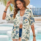 Stylish woman in a floral tassel cover-up, hat, and shorts, posing by a pool in a sunny beach setting.