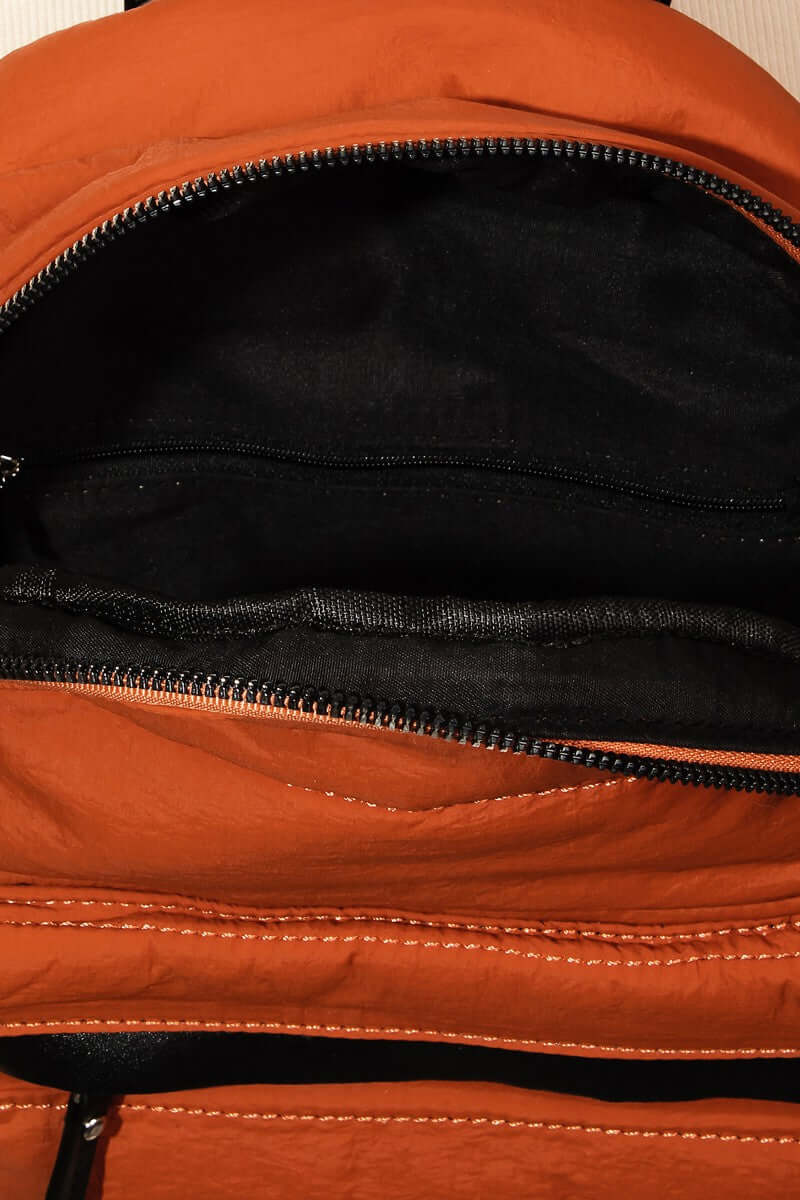 Inside view of an orange nylon backpack bag showcasing its spacious compartments and durable lining.