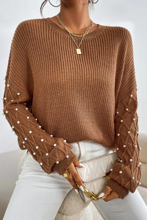 Bella Road Pearl Detail Round Neck Long Sleeve Sweater in brown, showcasing elegant pearl detailing on sleeves, worn with white pants.