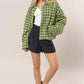 Stylish model in a green tweed plaid button-up collared neck jacket, paired with navy shorts and black shoes.