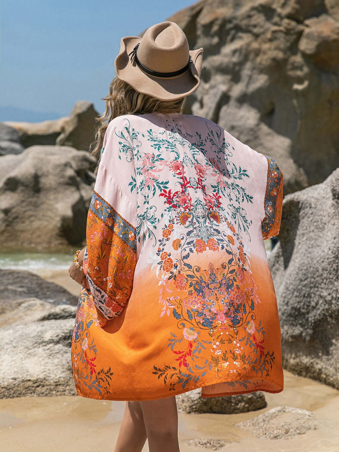 Stylish woman wearing Bella Road printed open front cover-up by the beach, features bright colors and floral patterns.