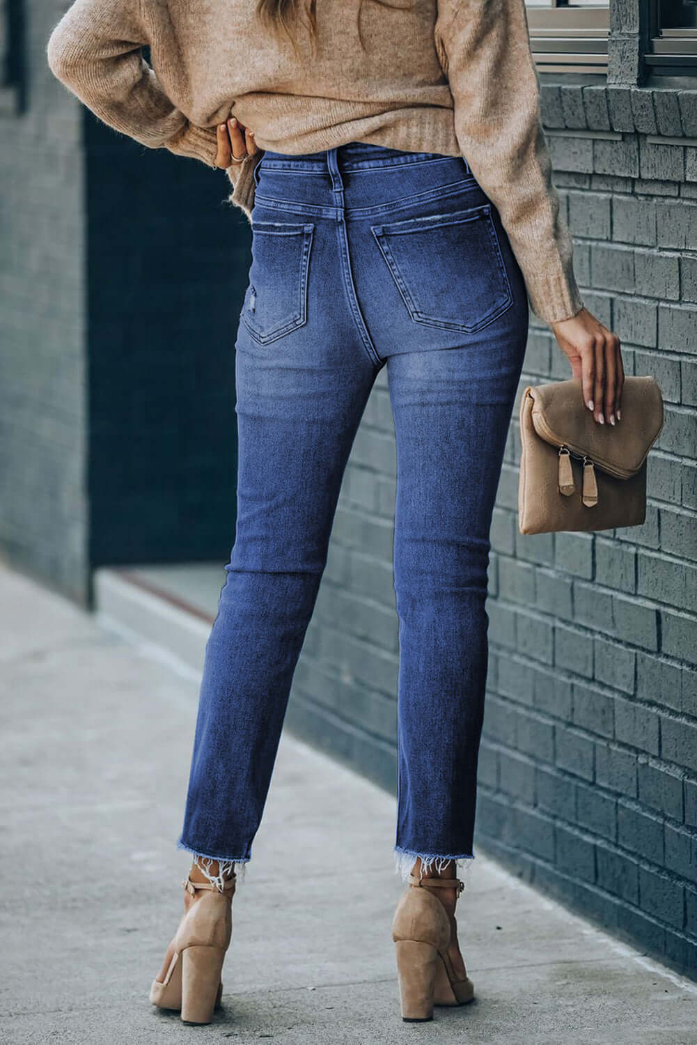 Woman wearing high waist raw hem skinny jeans with pockets, casual outdoor style with slightly stretchy cotton-polyester blend.