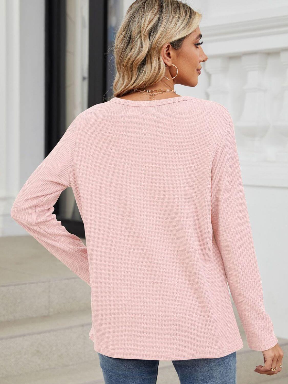 Woman wearing Bella Road waffle-knit notched long sleeve t-shirt in light pink, back view, standing outdoors with jeans.