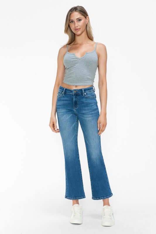 Model showcasing bytos Cat's Whiskers Mid Rise Ankle Jeans with a trendy cropped top and stylish sneakers.