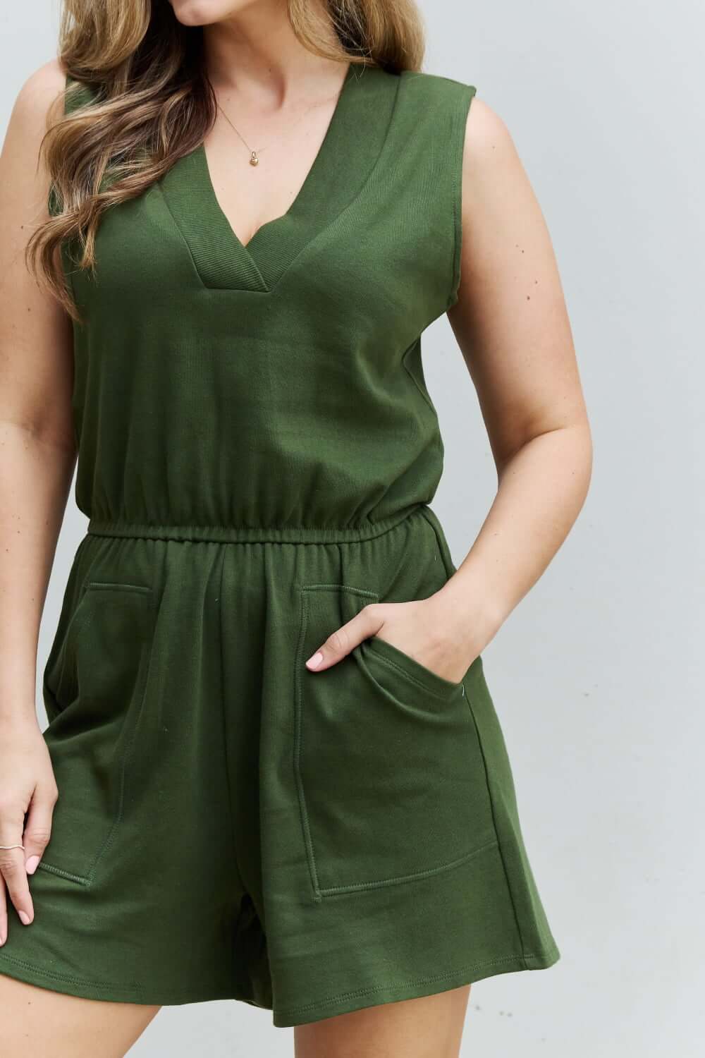 Woman wearing Forever Yours V-Neck Sleeveless Romper in Army Green, showcasing chic design and practical features for comfort and style.