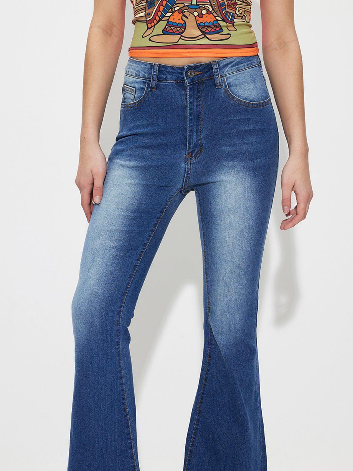 Woman wearing mid-rise waist bootcut jeans with pocket and button details, no stretch, 85% cotton and 15% polyester blend.