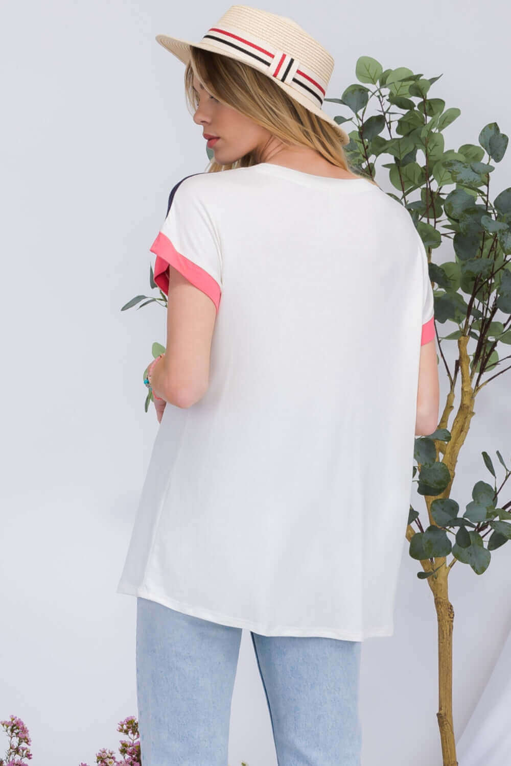 Woman wearing Color Block Round Neck Short Sleeve T-Shirt and hat, standing next to plant.