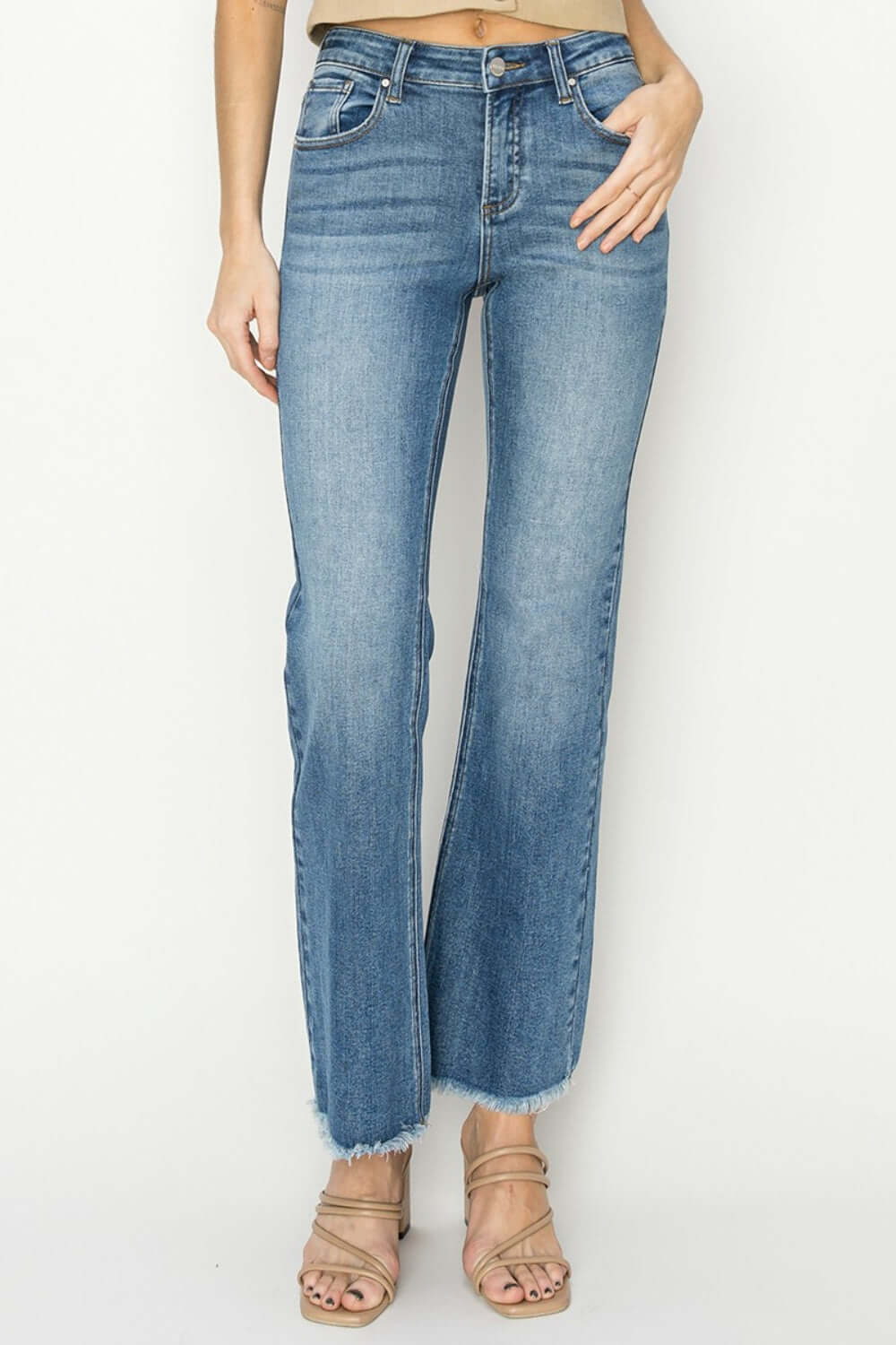 Mid-rise frayed hem bootcut jeans by Risen Jeans, showcasing trendy, edgy style, paired with sandals for a boho-chic look.