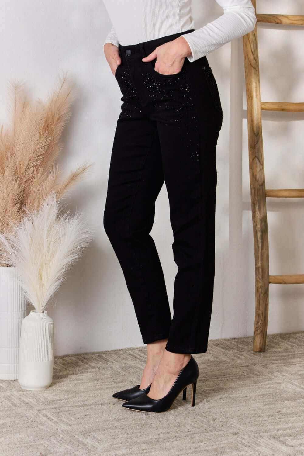 Woman wearing black rhinestone embellished slim Judy Blue jeans with high heels, highlighting the high waist design and trendy style.