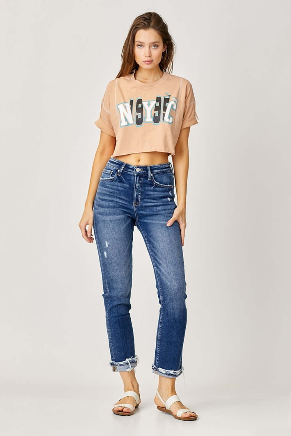 Woman wearing Risen Jeans High-Rise Frayed Cuffed Straight Jeans paired with a crop top and sandals.