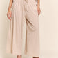 Woman wearing J.NNA smocked waist boho wide leg pants with pockets, showcasing stylish and comfortable fit.