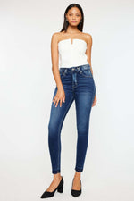 Woman wearing Kancan high-rise ankle skinny jeans in dark wash with double waistband and stylish release hem.