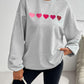 Gray Devine Heart Dropped Shoulder Long Sleeve Sweatshirt with pink heart design worn by a model