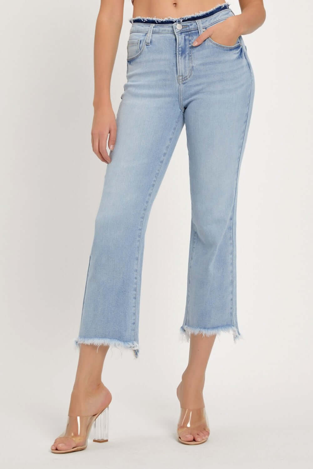 Woman wearing RISEN Full Size High Rise Raw Edge Crop Jeans with a raw hem, washed denim finish, and slightly stretchy material.