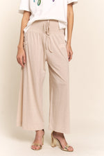 Boho wide leg pants with pockets and smocked waist, perfect for casual or dressy looks. Comfort meets style in relaxed beige pants.