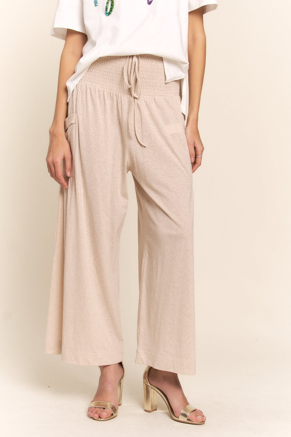 Boho wide leg pants with pockets and smocked waist, perfect for casual or dressy looks. Comfort meets style in relaxed beige pants.