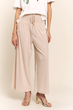 Boho wide leg pants with pockets and smocked waist, perfect for casual or dressy looks. Comfort meets style in relaxed beige pants.