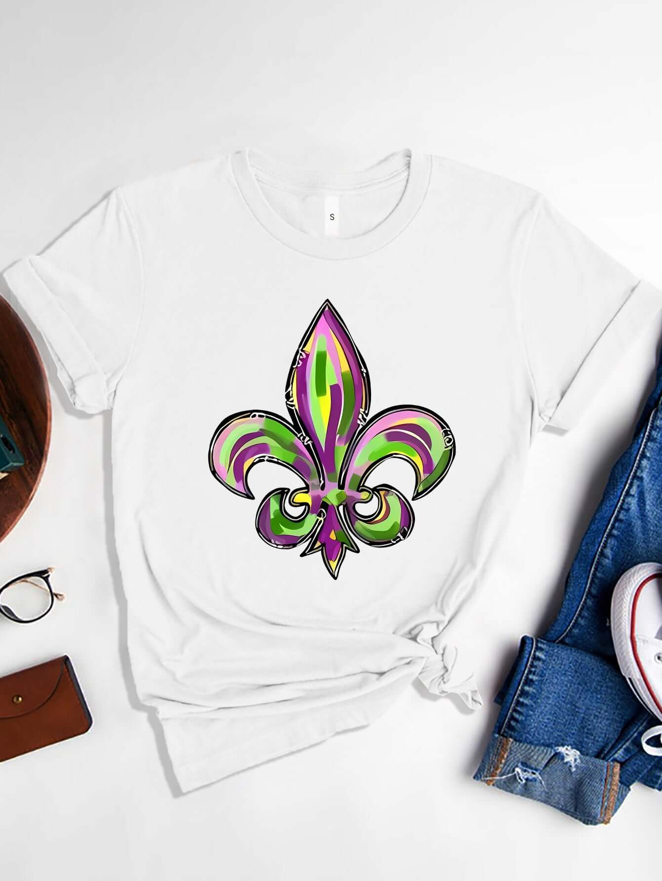 Bella Road Mardi Gras white t-shirt featuring a vibrant green and purple fleur-de-lis graphic design. Perfect for festive celebrations!