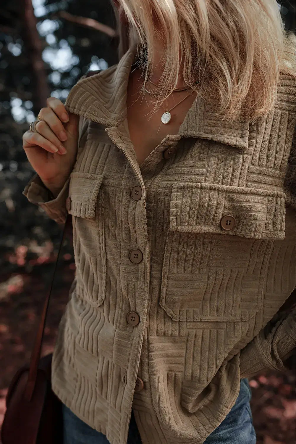 Woman wearing a textured pocketed collared neck long sleeve shacket in outdoor setting.